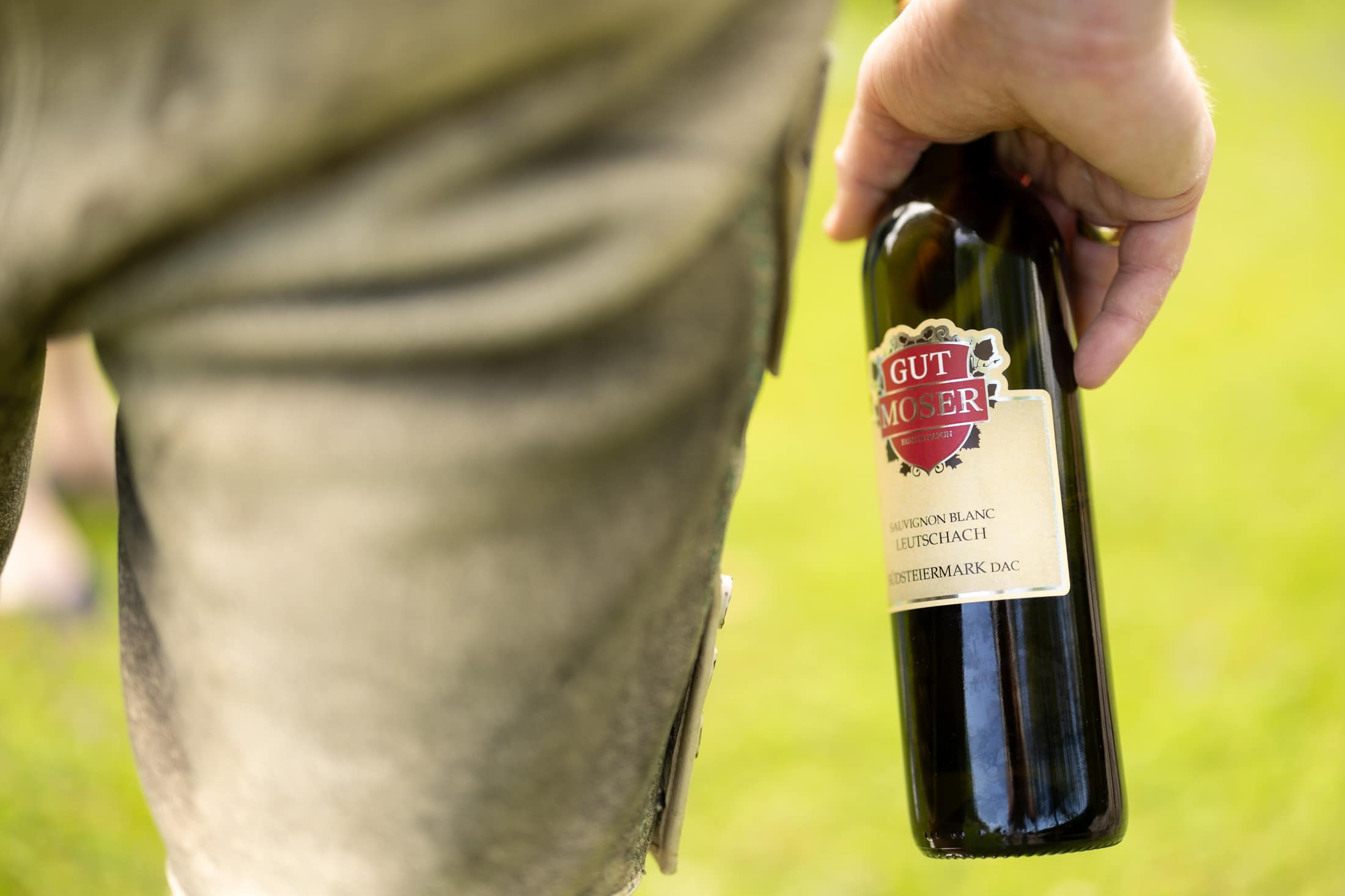 Detailaufnahme wie jemand eine Flasche Wein von Gut Moser in der Hand hält