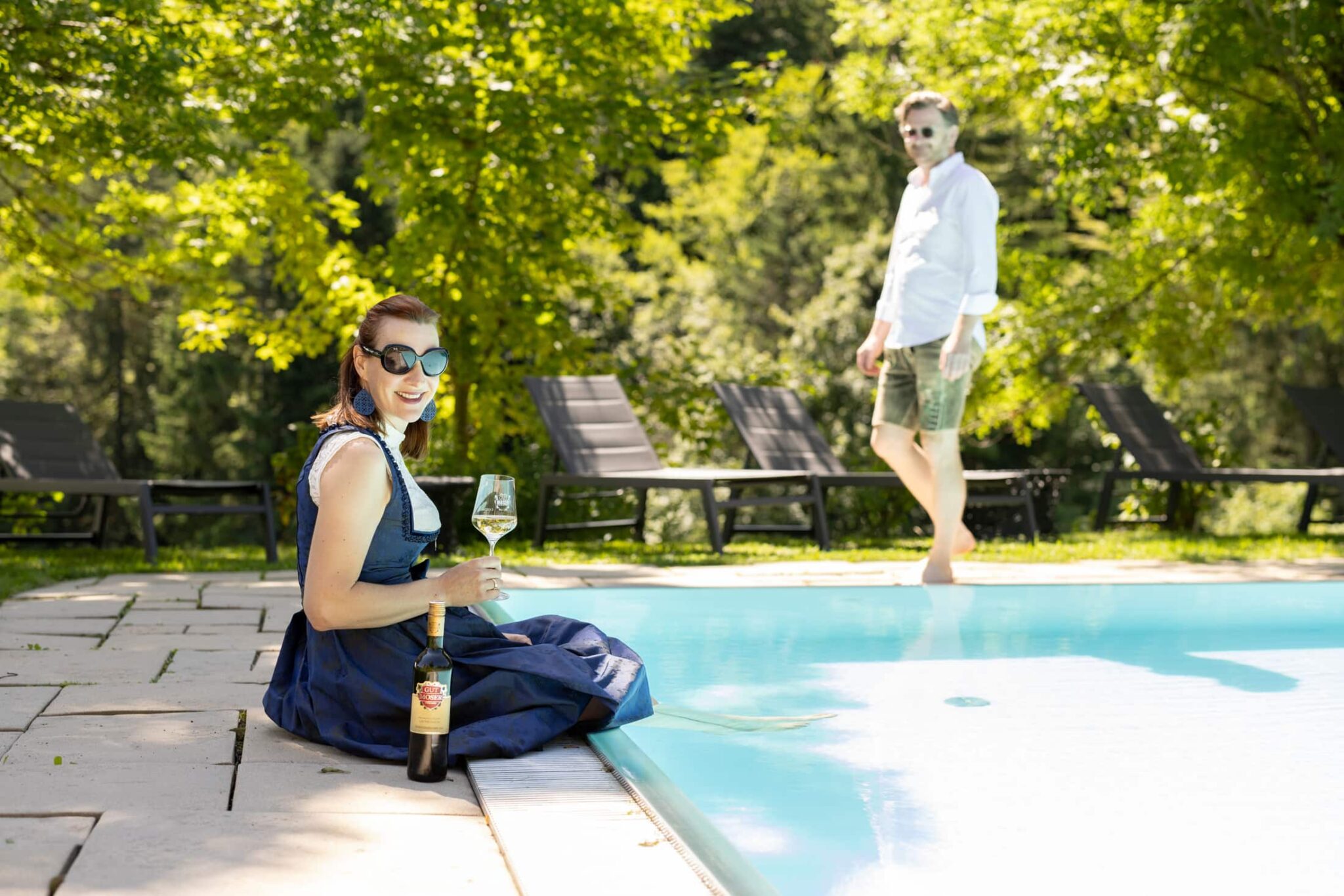 Eine Frau genießt ein Glas Wein am Pool des Winzerhotel Gut Moser.
