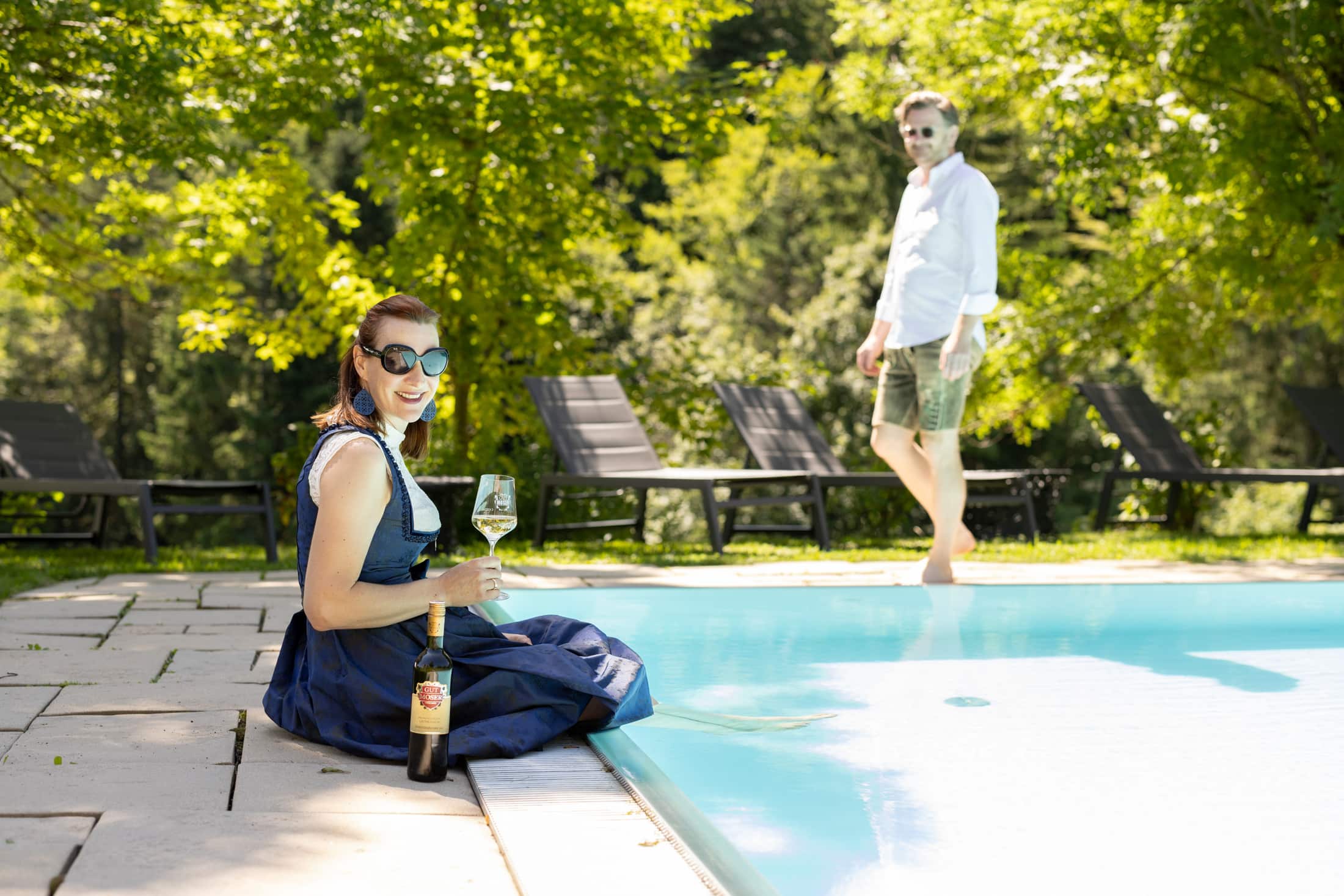 Frau genießt ein Glas Wein am Pool